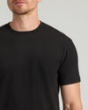 Person wearing a plain black t-shirt against a neutral background