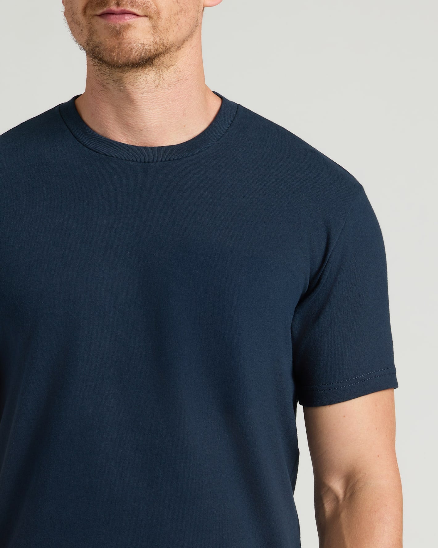 Man wearing a navy blue t-shirt with a pocket on a light gray background