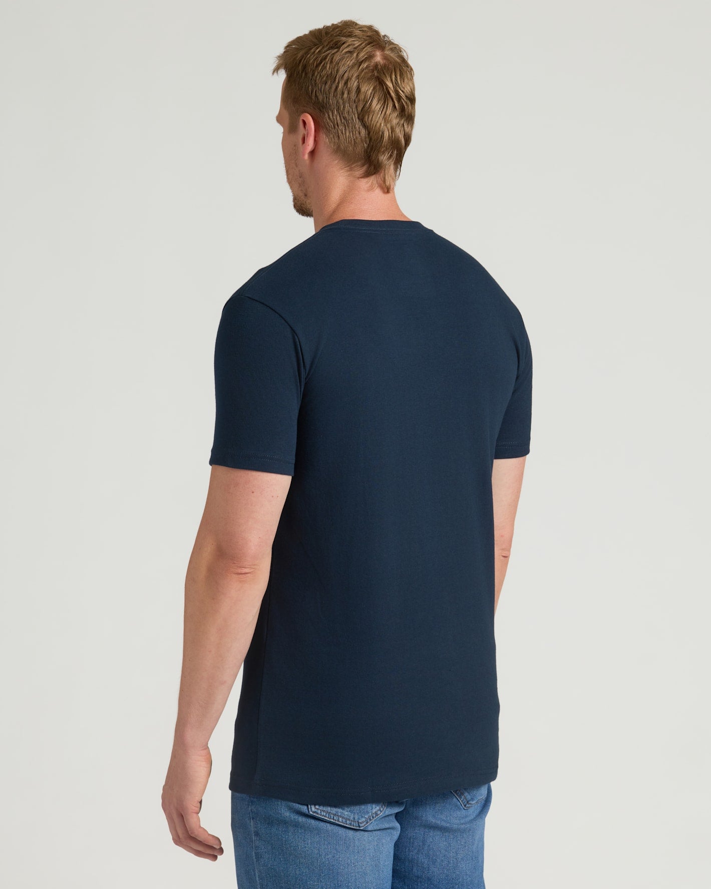 Man wearing a navy blue t-shirt on a light gray background