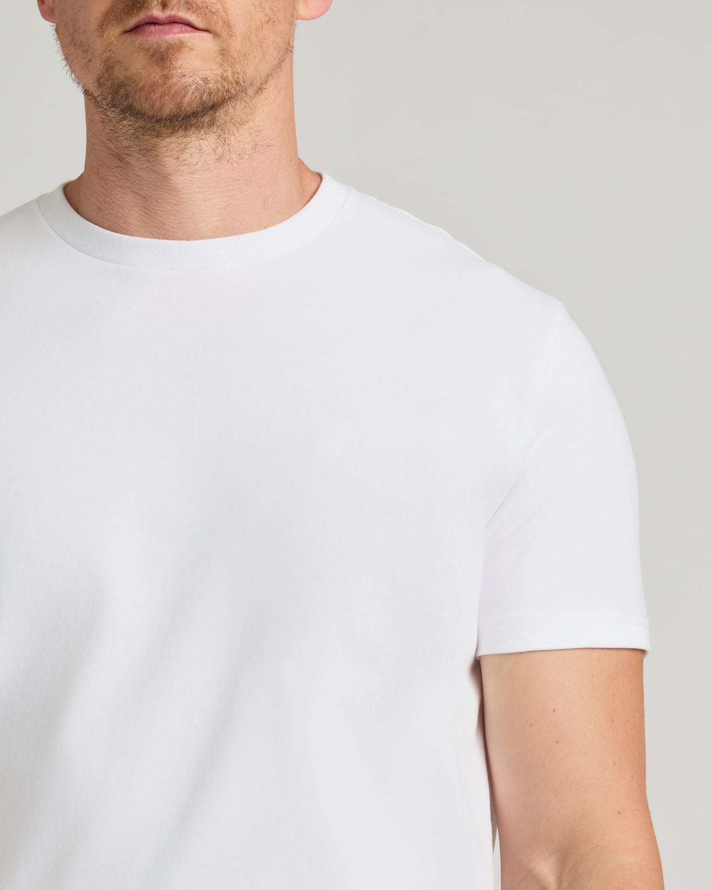 Man wearing a plain white t-shirt against a neutral background