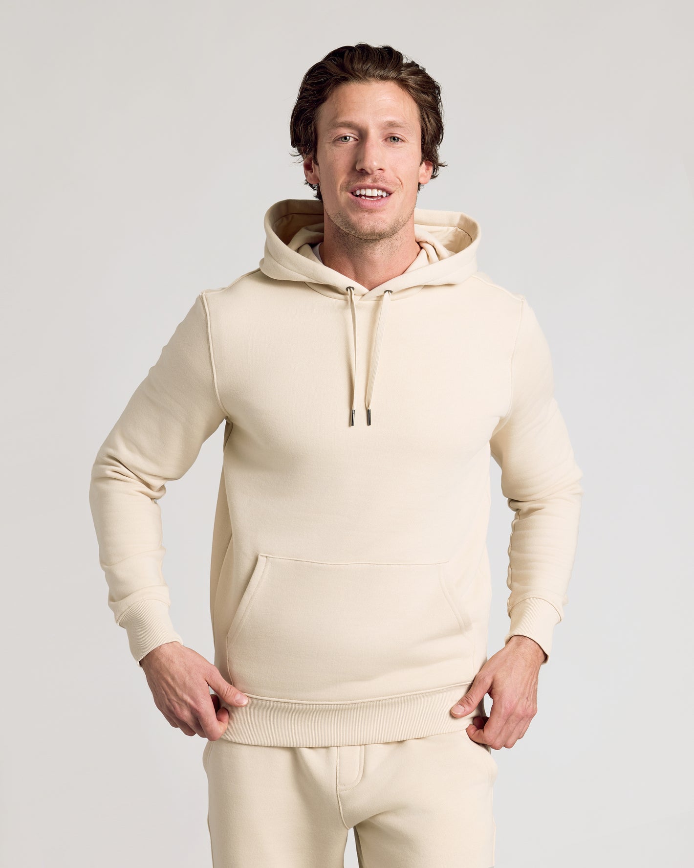 Man in Dune Fleece French Terry Pullover Hoodie, hands on hem.