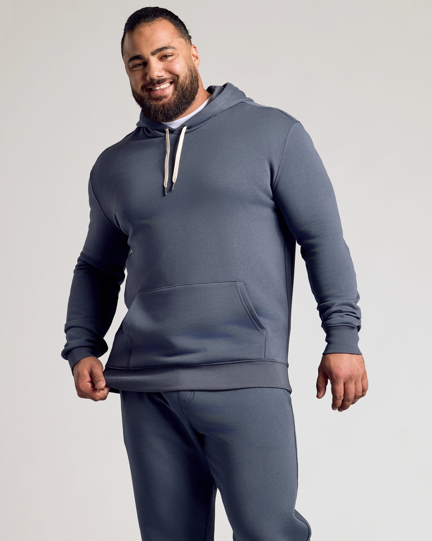 Man wearing Stormy Fleece French Terry Pullover Hoodie, smiling.