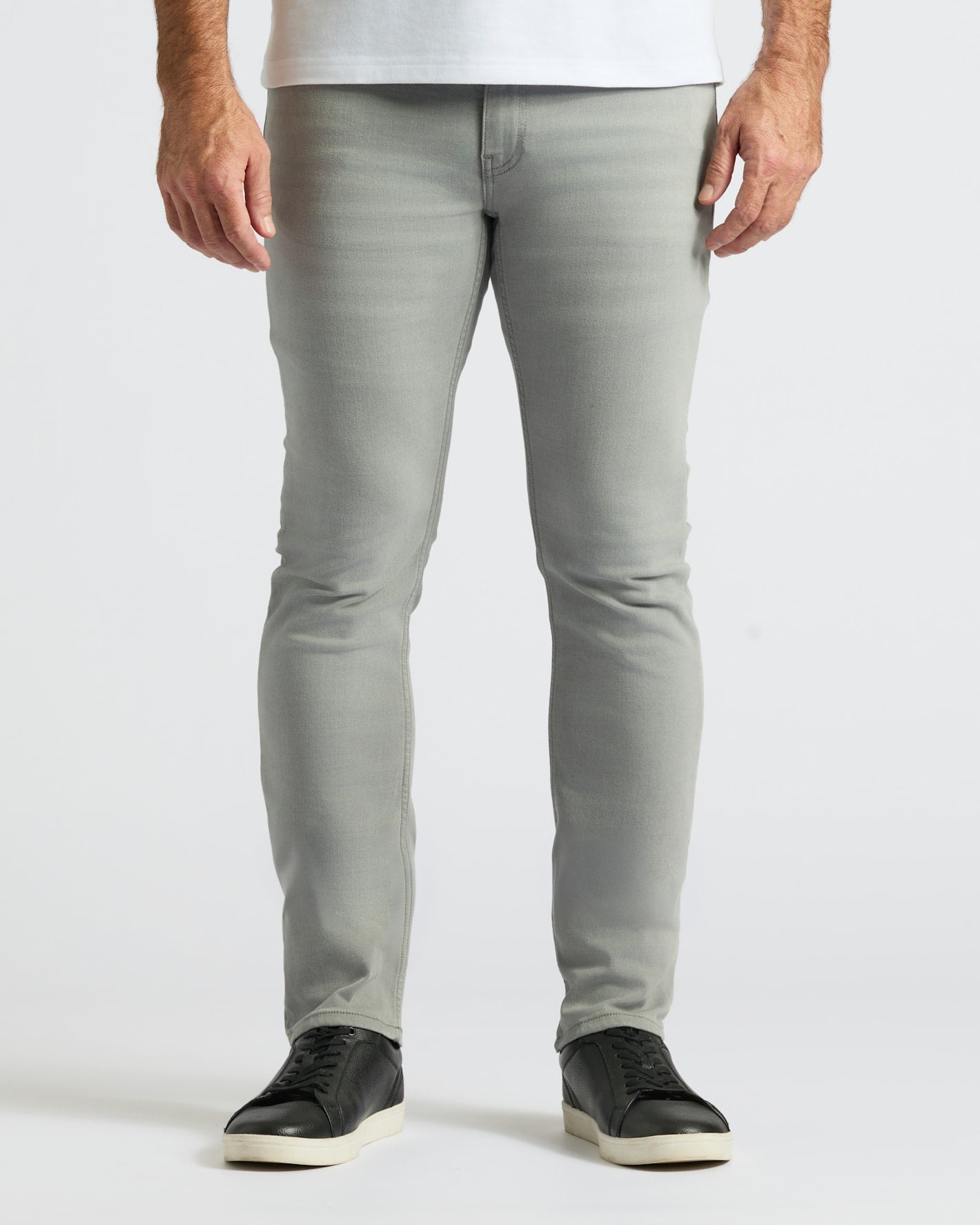 Front view of a man wearing Gray Medium Indigo Slim Comfort Stretch Jeans 3-Pack paired with black sneakers against a plain white background.