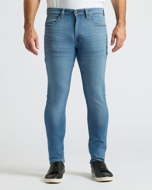 Medium Indigo Wash Slim Comfort Stretch Jeans with black sneakers, front view.