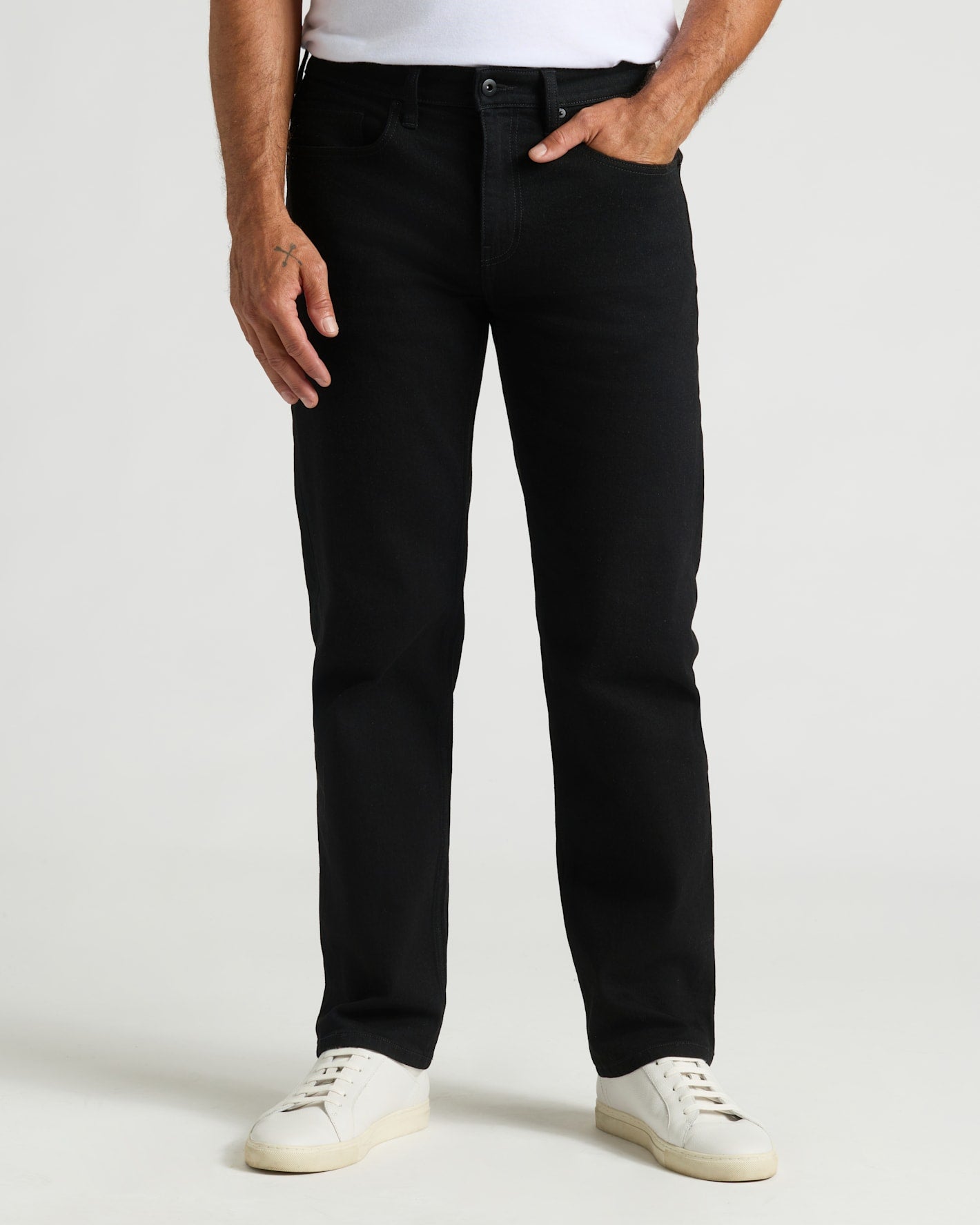 Black Wash Straight Authentic Denim Jeans with white sneakers, model's hand in pocket.