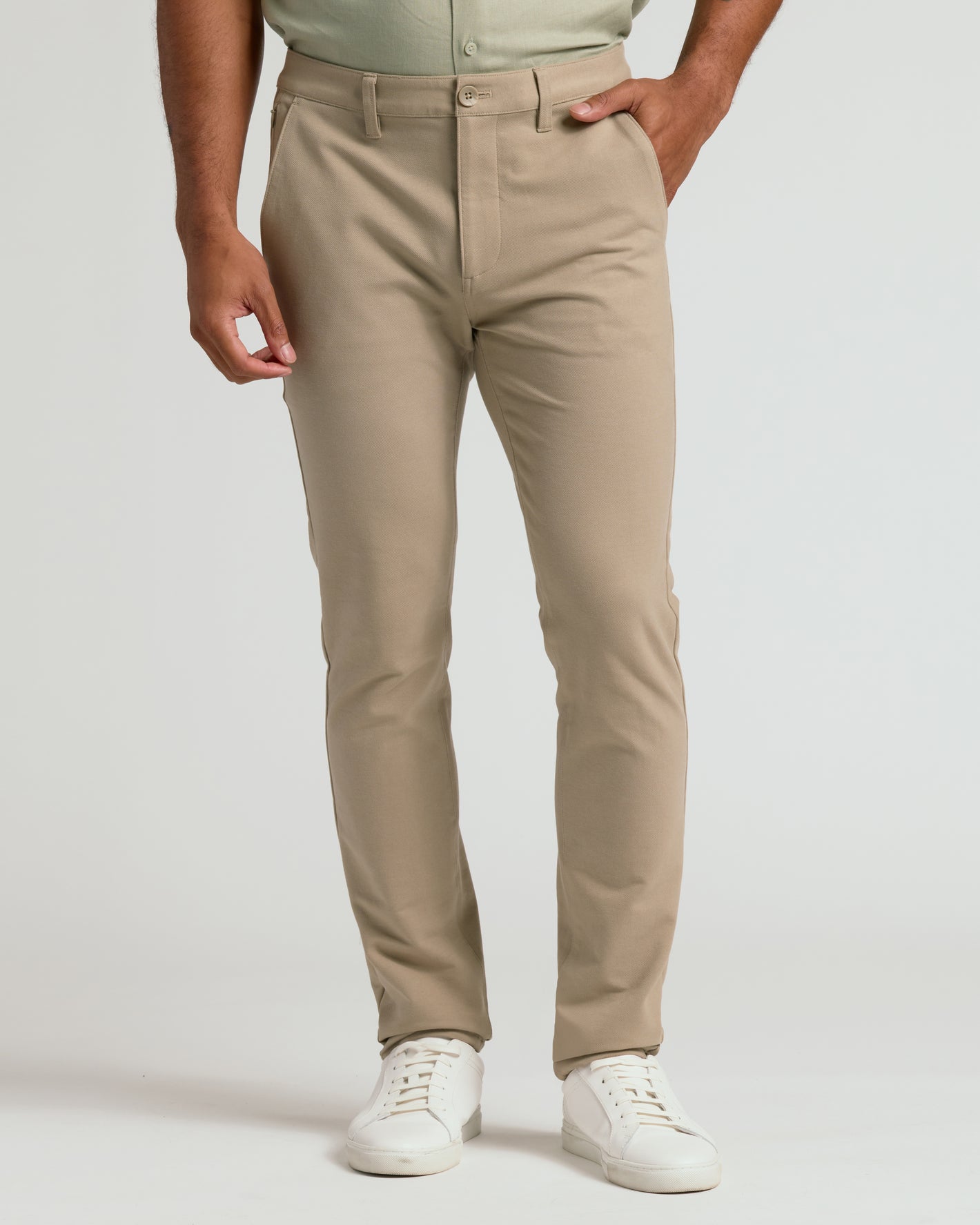 Khaki Slim Chino Pants 2.0 with white sneakers, hand in pocket.