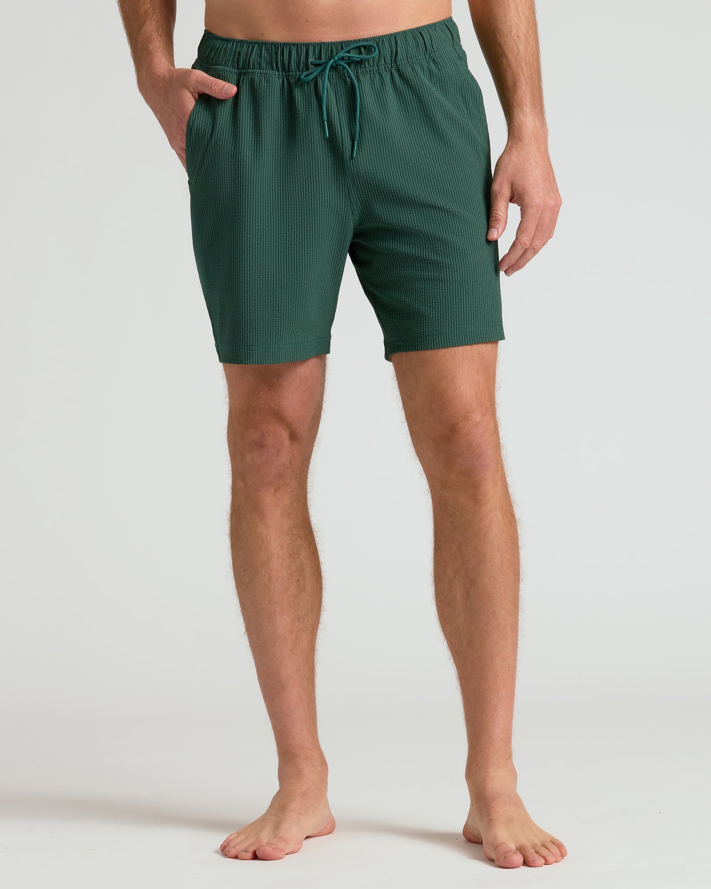 Model wearing 7 Marine Spruce Seersucker Swim Trunks with side pockets.