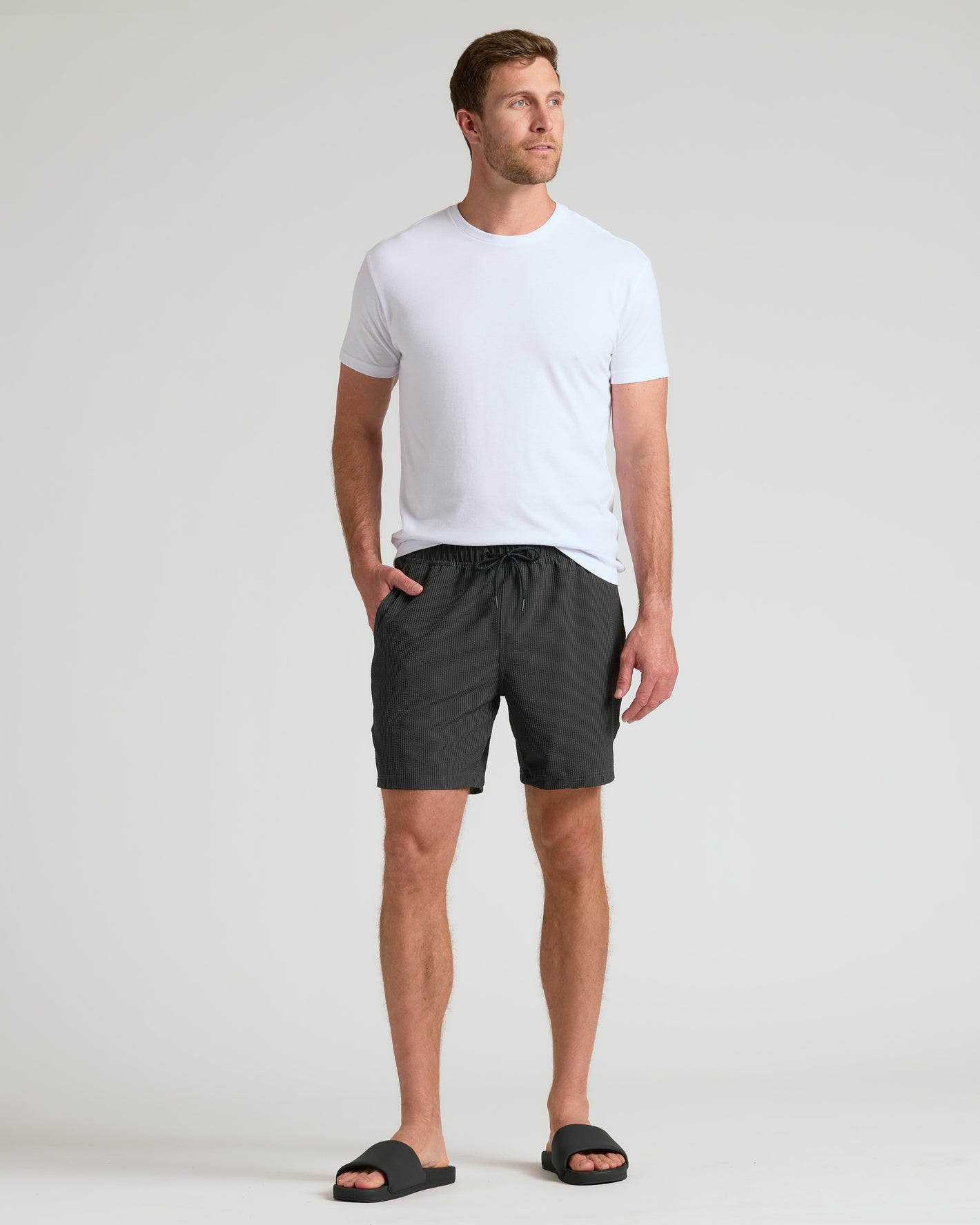 Man wearing 7 Smoke Seersucker Swim Trunks with black sandals.