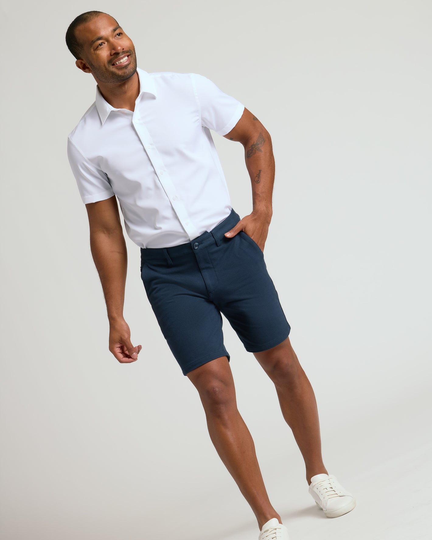 Man wearing 9 Navy Classic Chino Shorts 2.0, white shirt, sneakers.