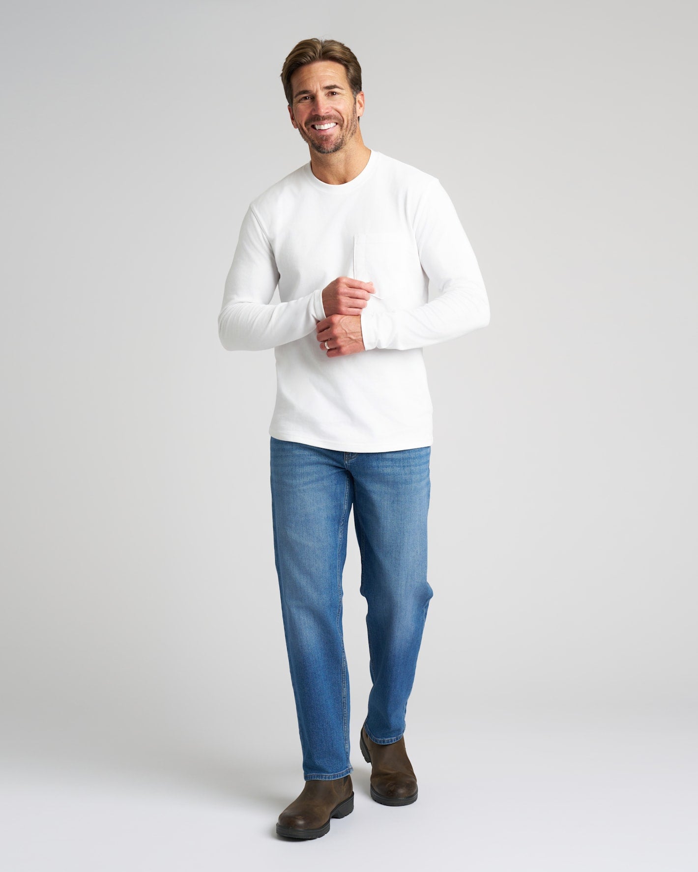 Man wearing True Classic x Timberland Pro Chelsea Boots, smiling against gray background.
