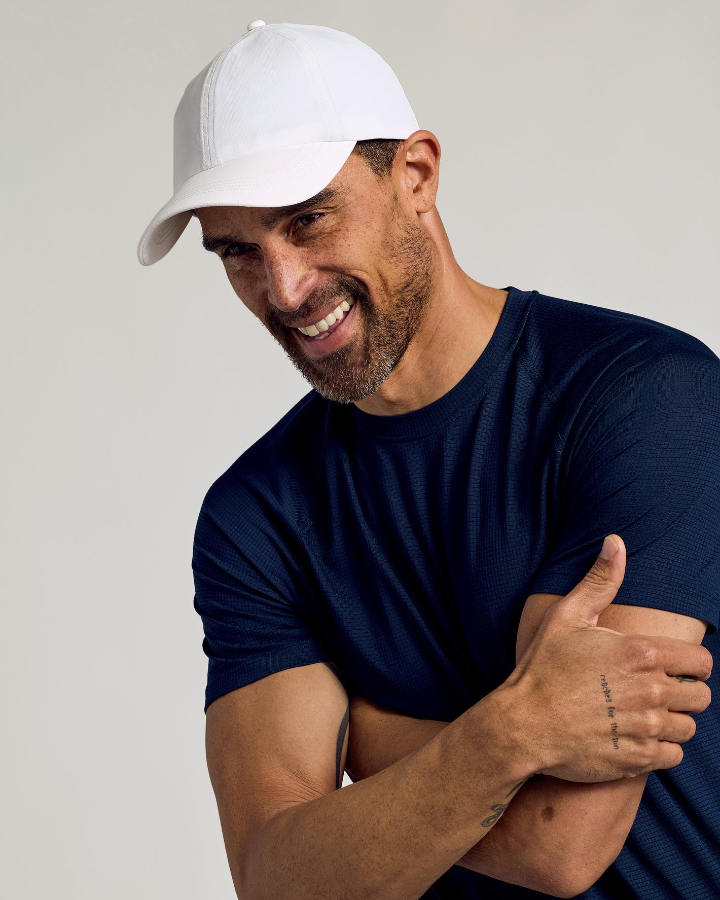 Man wearing White Active Running Cap, navy T-shirt, arms crossed.