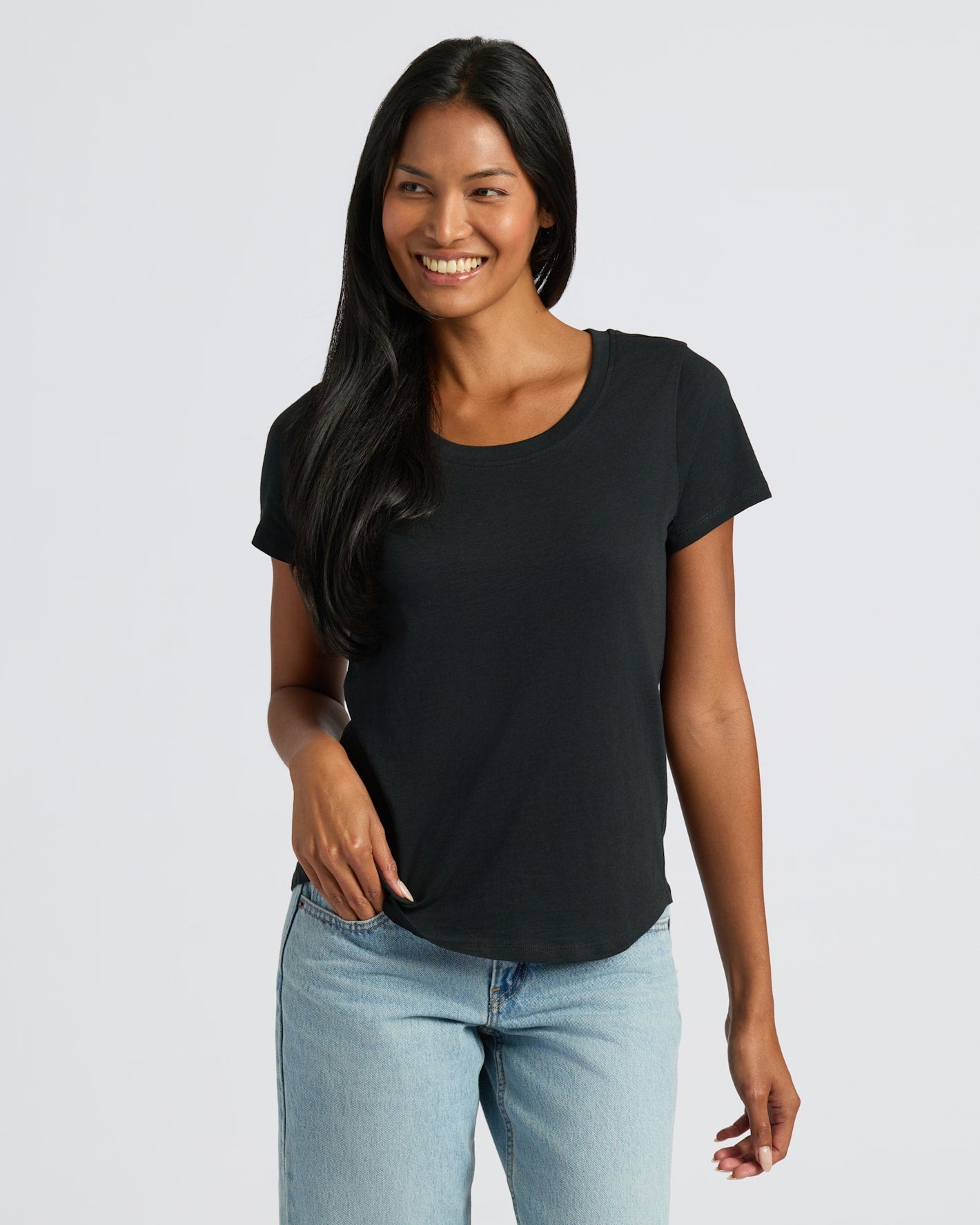Woman wearing a black t-shirt and light blue jeans on a white background