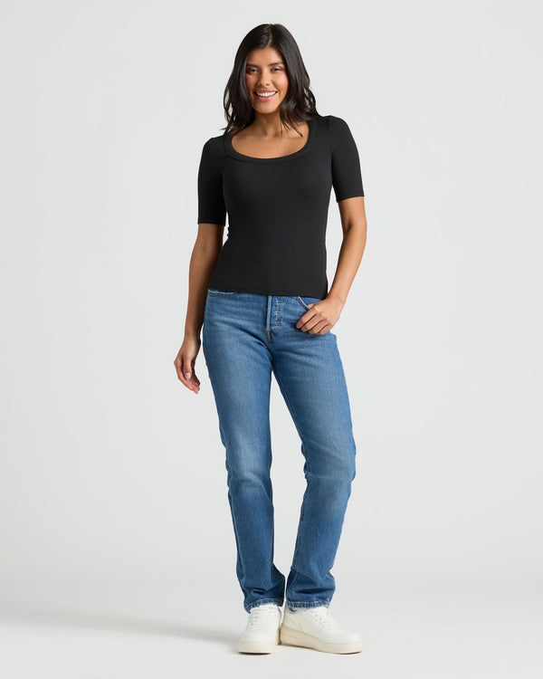 Woman in black ribbed 3/4 sleeve scoop neck tee with jeans.