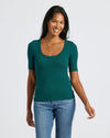 Woman wearing a green top and blue jeans on a white background