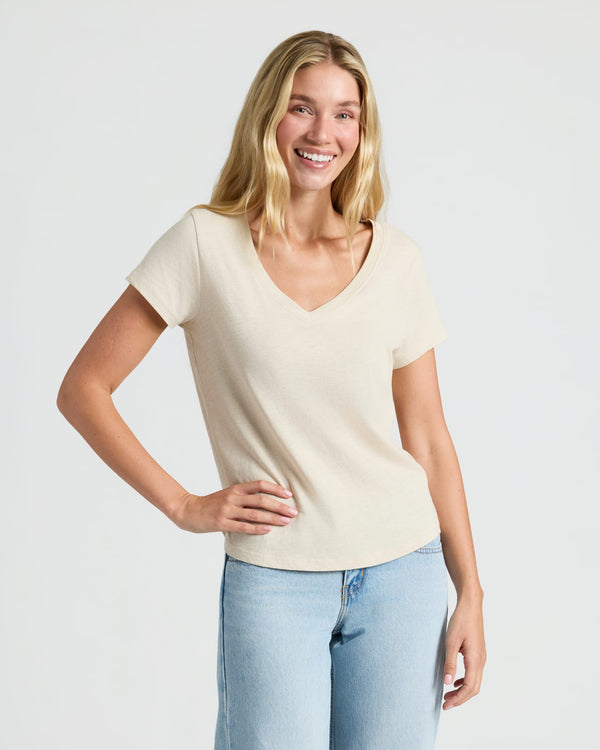 Woman in cream V-neck tee and jeans, showcasing Womens Oatmeal Relaxed Slub V-Neck Tee 4-Pack. MODEL_INFO: Cora is 5'10", wearing a size S