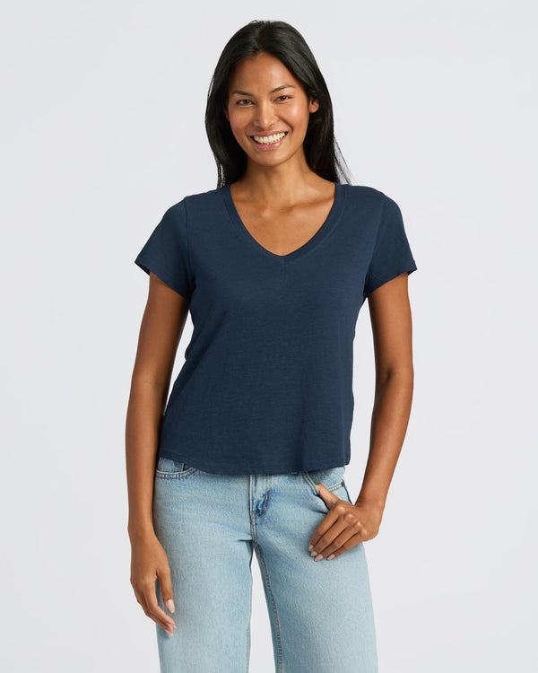 Woman in navy V-neck tee and jeans, smiling casually. MODEL_INFO: Candy is 5'9", wearing a size S