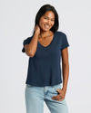 Woman wearing a navy blue t-shirt and light blue jeans on a white background. MODEL_INFO: Candy is 5'9", wearing a size S