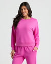 Woman wearing a pink sweatshirt and pants on a white background