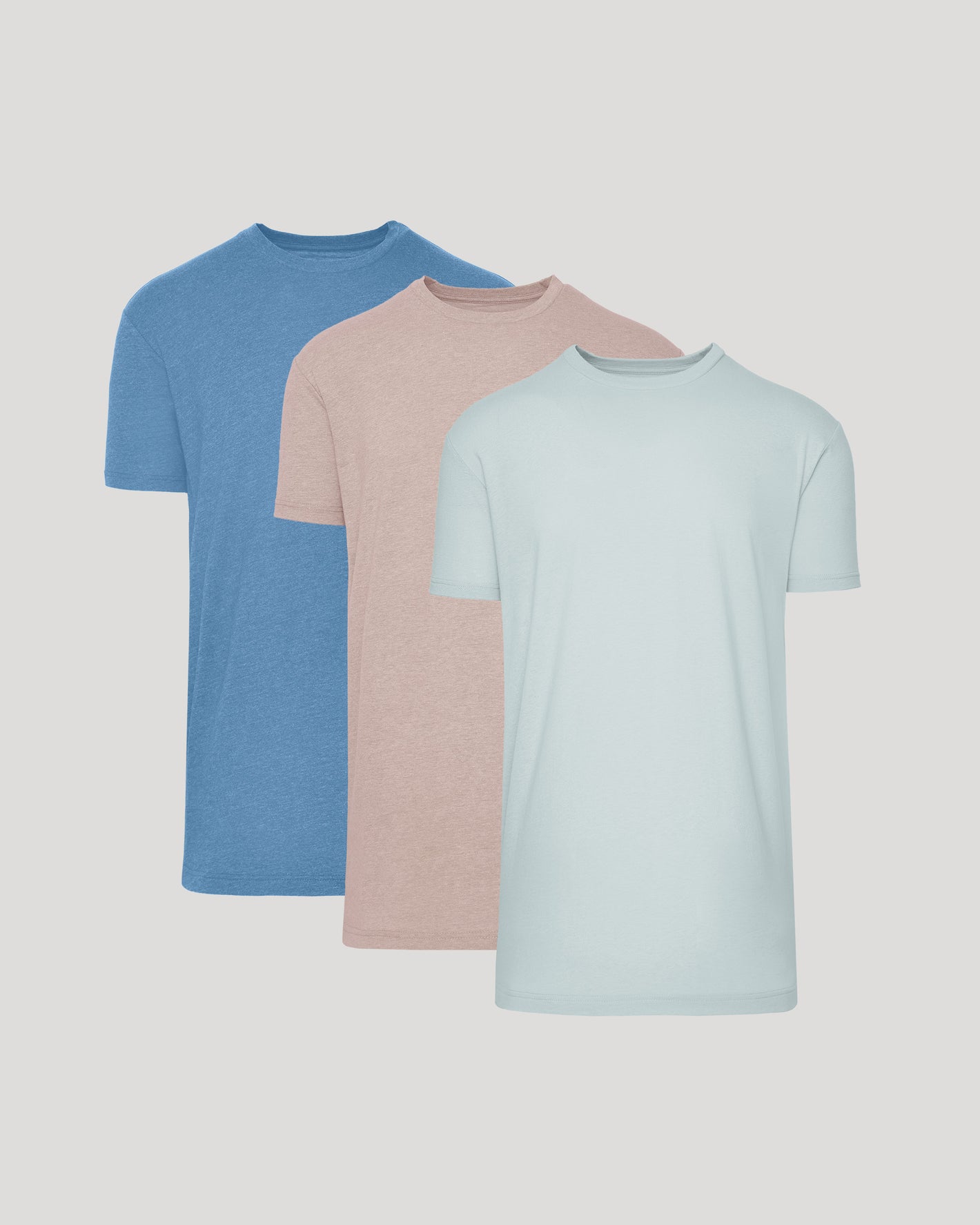 Three plain t-shirts in blue, pink, and light blue on a gray background