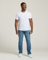 Man wearing a white t-shirt and blue jeans against a plain background