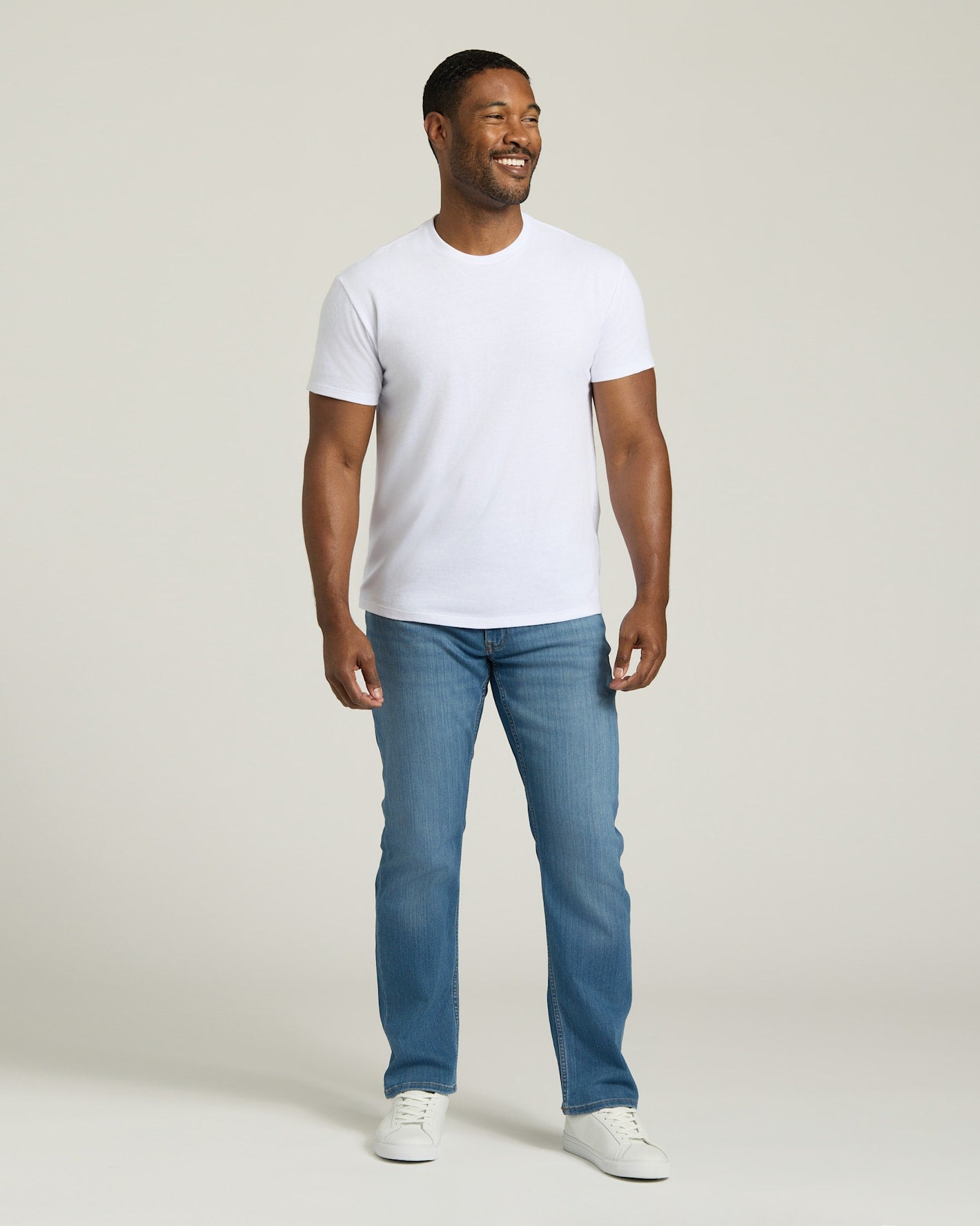 Man wearing a white t-shirt and blue jeans against a plain background