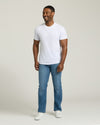 Man wearing a white t-shirt and blue jeans on a plain background