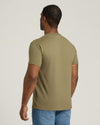 Man wearing a green t-shirt and blue jeans on a plain background