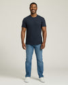 Man wearing a navy t-shirt and blue jeans on a white background