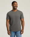 Man wearing a gray t-shirt and blue jeans against a plain background