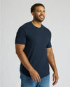 Man wearing a navy blue True Classic Men's Tall Heavyweight Curved Hem Crew – Premium Heavyweight Cotton Blend, Extended Length, Athletic Fit, Structured Everyday T-Shirt with jeans, smiling and looking to the side.