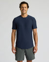 Man wearing a navy blue t-shirt and gray shorts on a light gray background