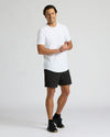 Man wearing a white t-shirt and black shorts on a light gray background