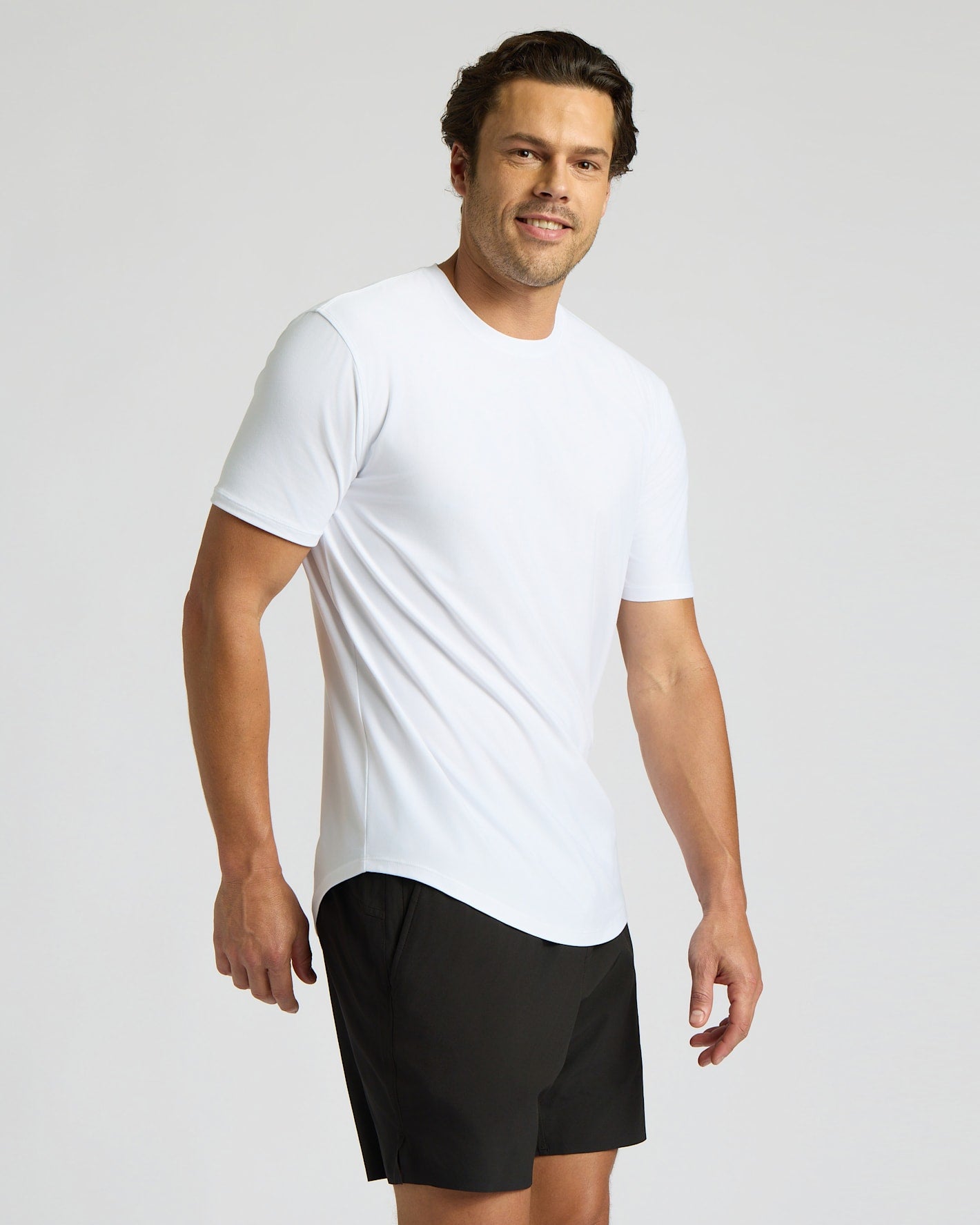 Man wearing a white t-shirt and black shorts on a light gray background