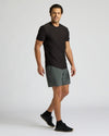 Man wearing a black t-shirt and gray shorts on a white background