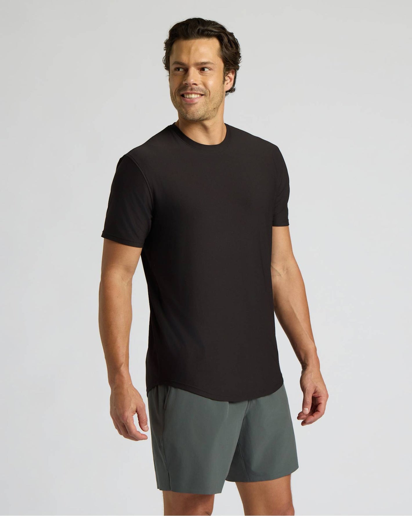 Man wearing a black t-shirt and gray shorts on a light gray background