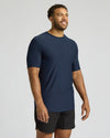 Man wearing a navy blue athletic shirt and black shorts on a light gray background