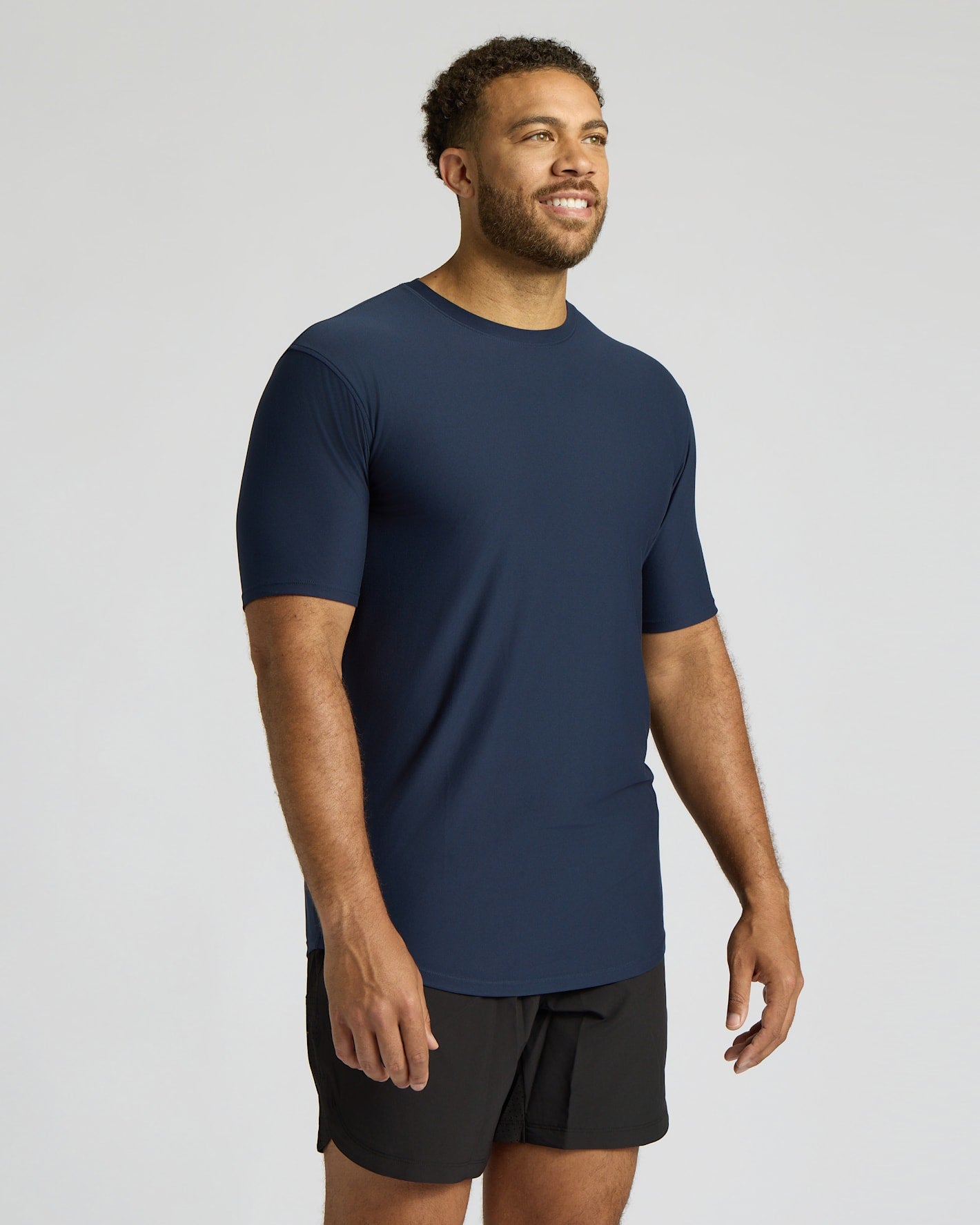 Man wearing a navy blue athletic shirt and black shorts on a light gray background