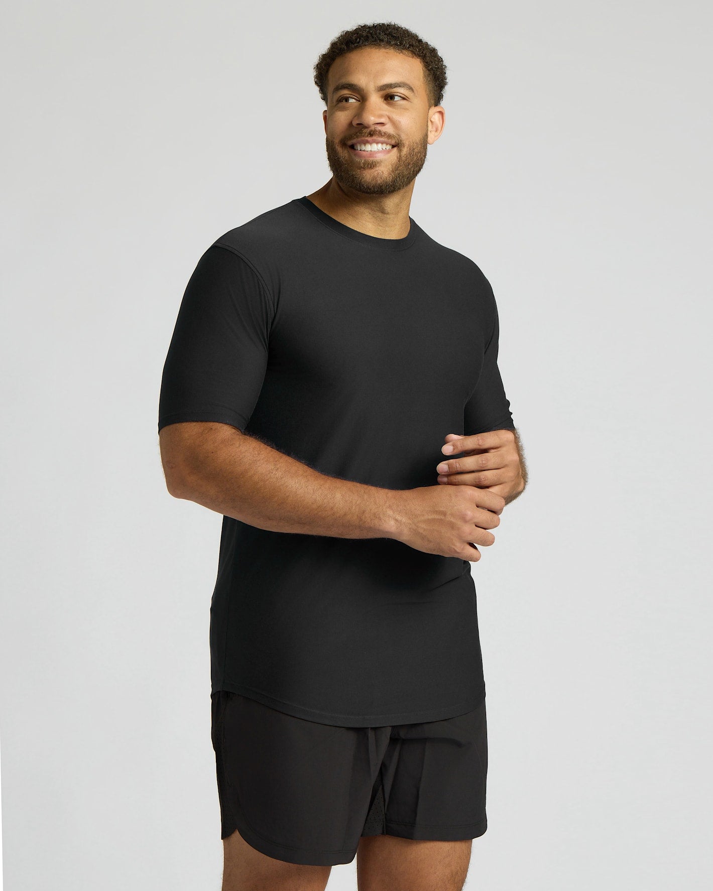 Man wearing a black t-shirt and shorts on a gray background