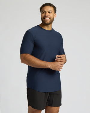 Man wearing a navy blue t-shirt and black shorts on a light gray background