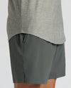 Close-up of a person wearing heather gray athletic shorts and the lower portion of a gray long-sleeve top against a light gray studio background.