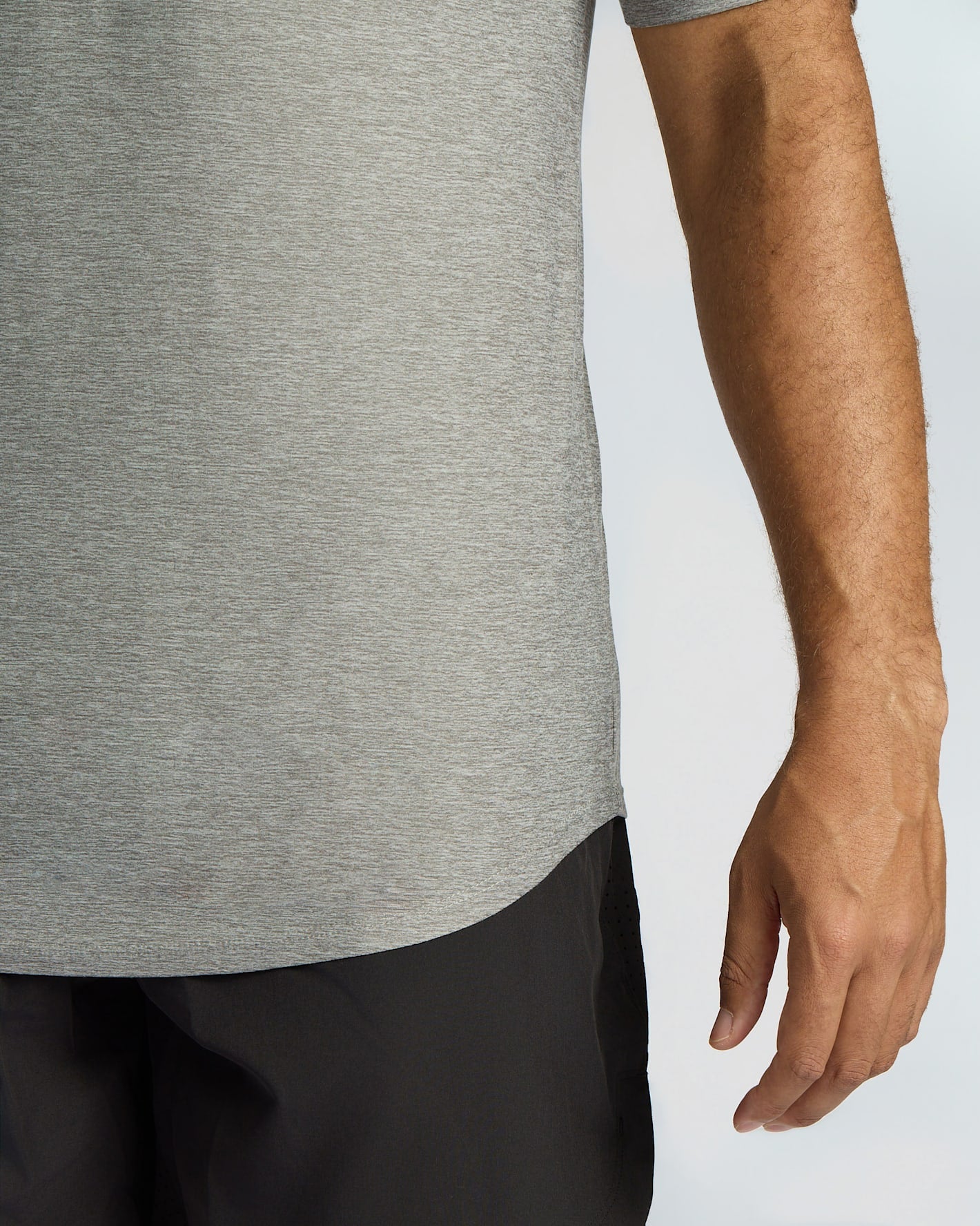 Close-up of a person wearing a heather gray short-sleeve top and black pants against a light gray background.
