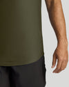 Close-up of a person wearing an olive green athletic top and dark shorts against a light gray background.