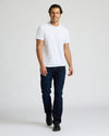 Man wearing a white t-shirt and dark jeans on a plain background