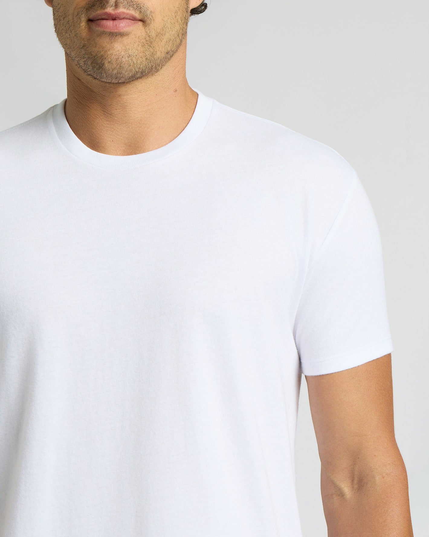 Man wearing a plain white t-shirt against a light gray background
