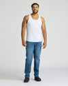 Man wearing a white tank top and blue jeans on a white background