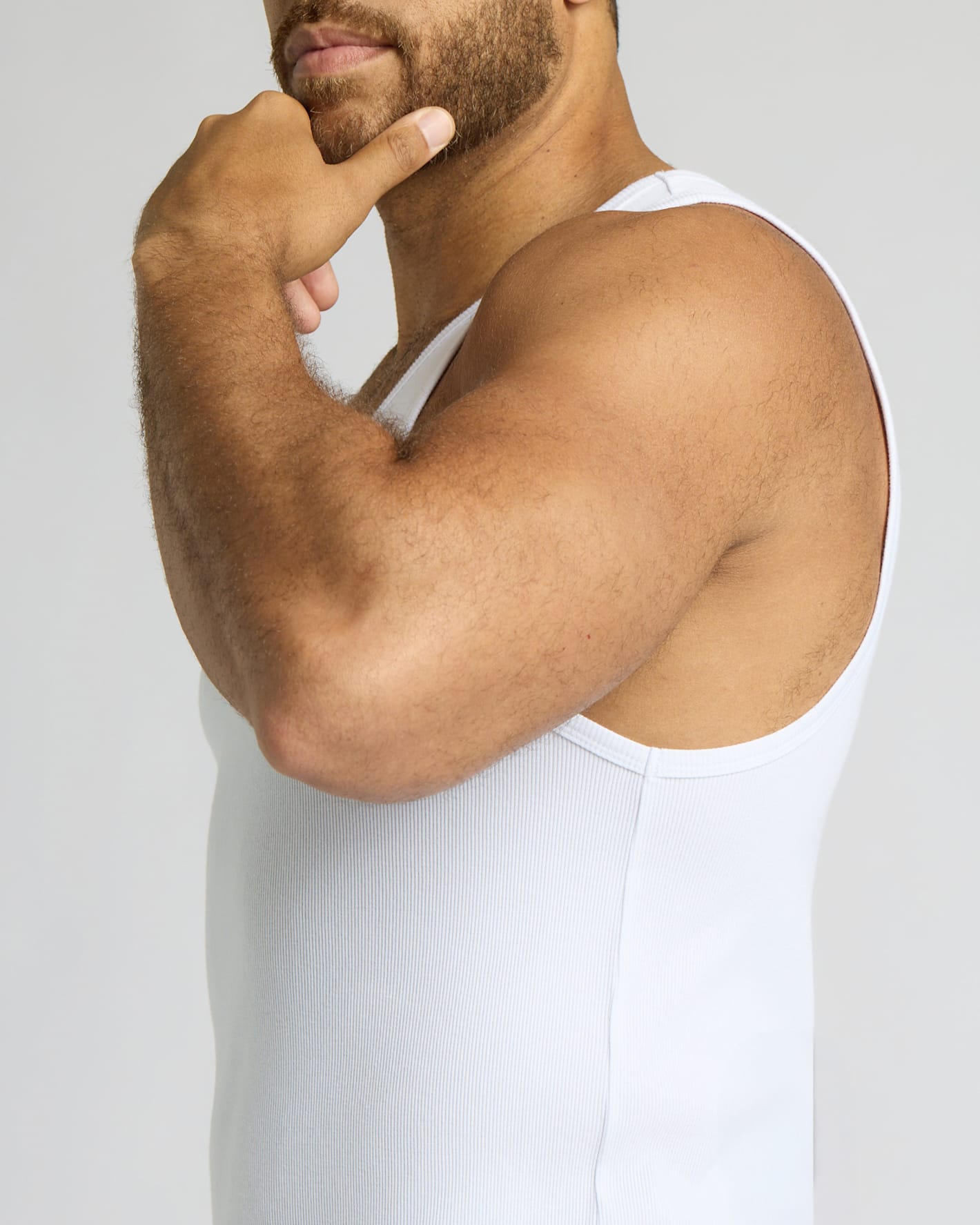 Man wearing a white tank top against a light gray background
