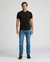 Man wearing a black t-shirt and blue jeans on a white background