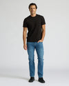 Man wearing a black t-shirt and blue jeans on a white background
