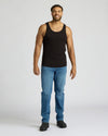 Man wearing a black tank top and blue jeans on a white background