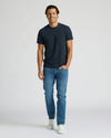 Man wearing a navy t-shirt and blue jeans on a white background